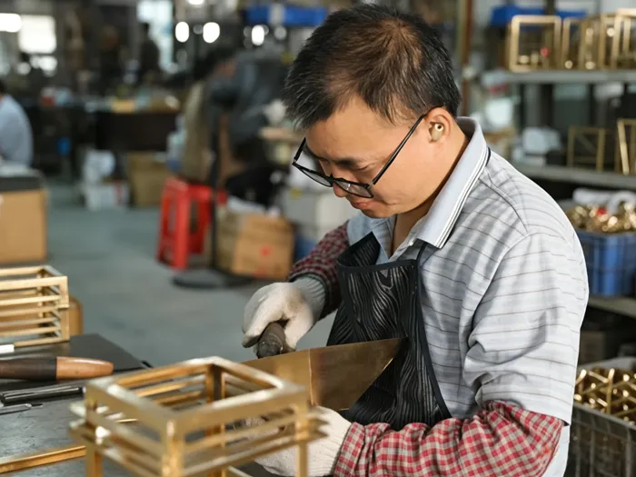 Artisan hand-soldering solid brass lantern in workshop