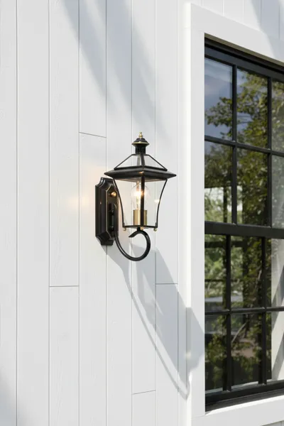 Black wall lantern on white house siding beside window
