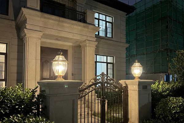 Pair of brass pier mount lanterns on stone gate pillars at night